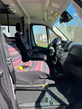 Inside this RV rental, see the roomy driver's cabin with vibrant striped seat covers and a clean dashboard.