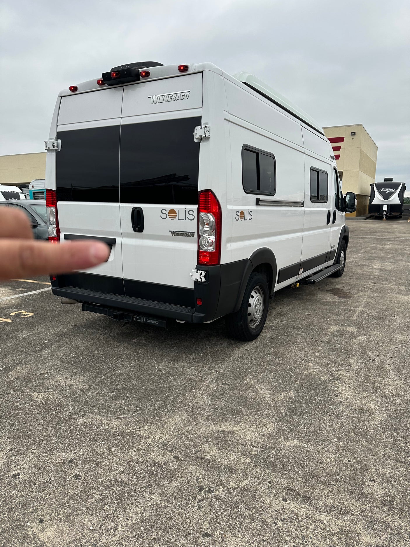 This white Winnebago Solis camper van, ready for your RV rental adventure, is parked on a spacious lot.