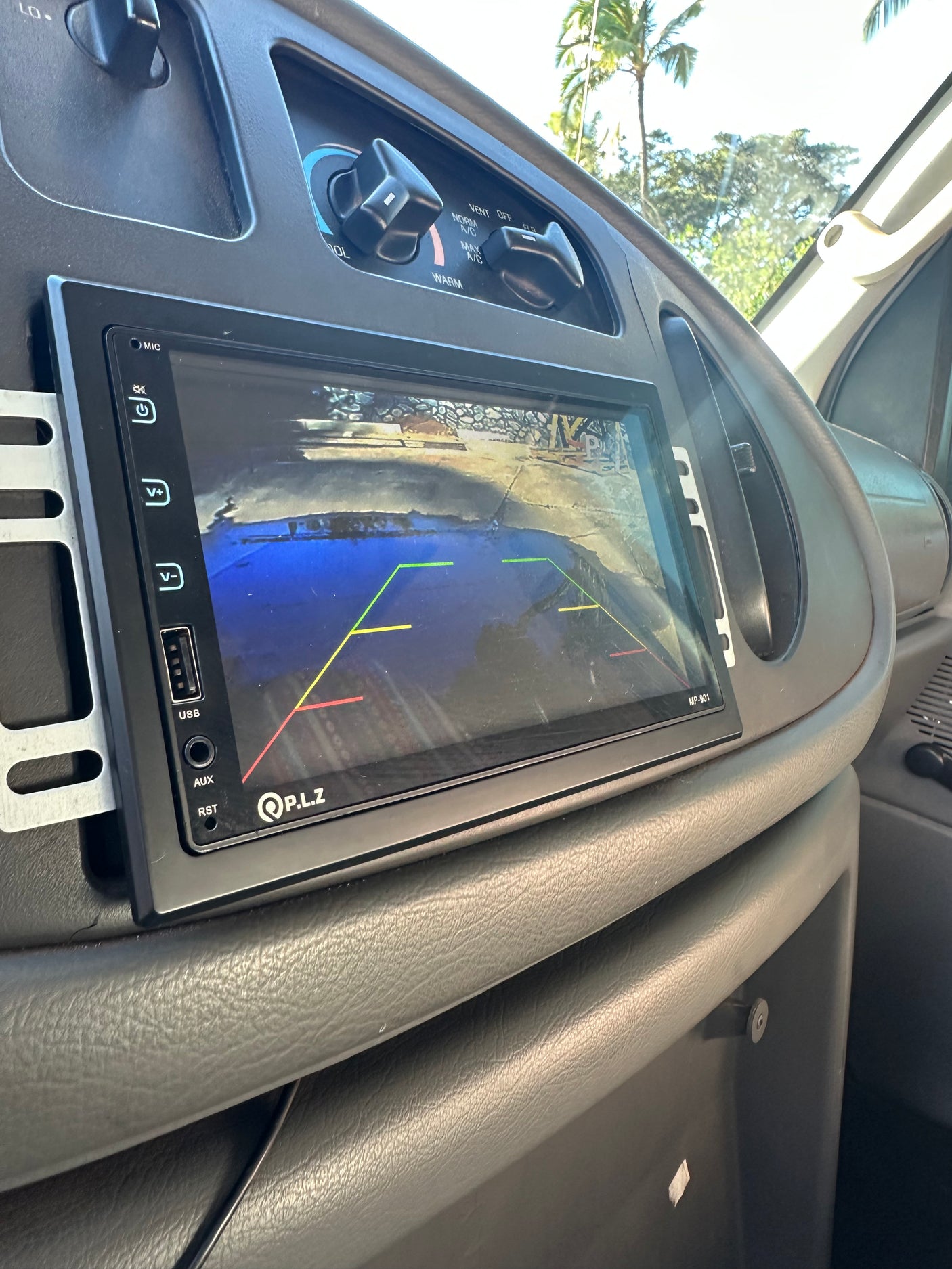 Inside an rv rental: P.L.Z infotainment screen showing a backup camera view with parking lines. Dashboard and HVAC controls.