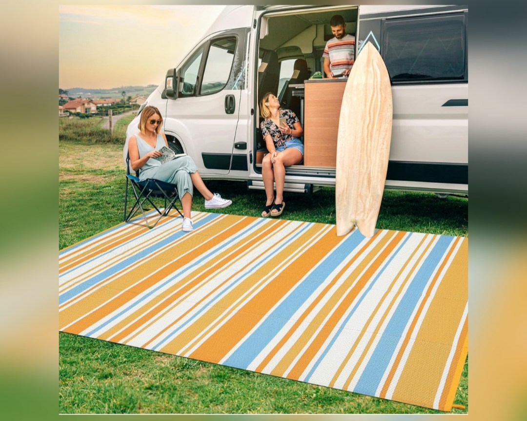 Friends relax on a striped outdoor mat outside their RV rental, with a surfboard nearby. Perfect for camping adventures! — photo 16