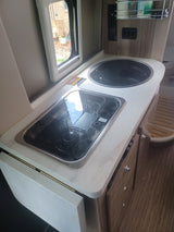Inside an rv rental: a functional compact kitchen featuring an integrated sink, two-burner stovetop, and clever storage.