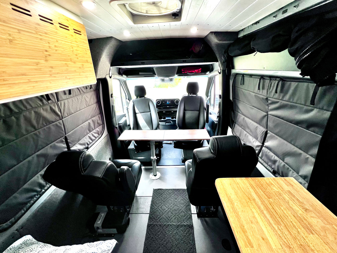 Inside a modern rv rental camper van: swivel seats, dining table, and insulated walls, ready for comfortable travel. — photo 10