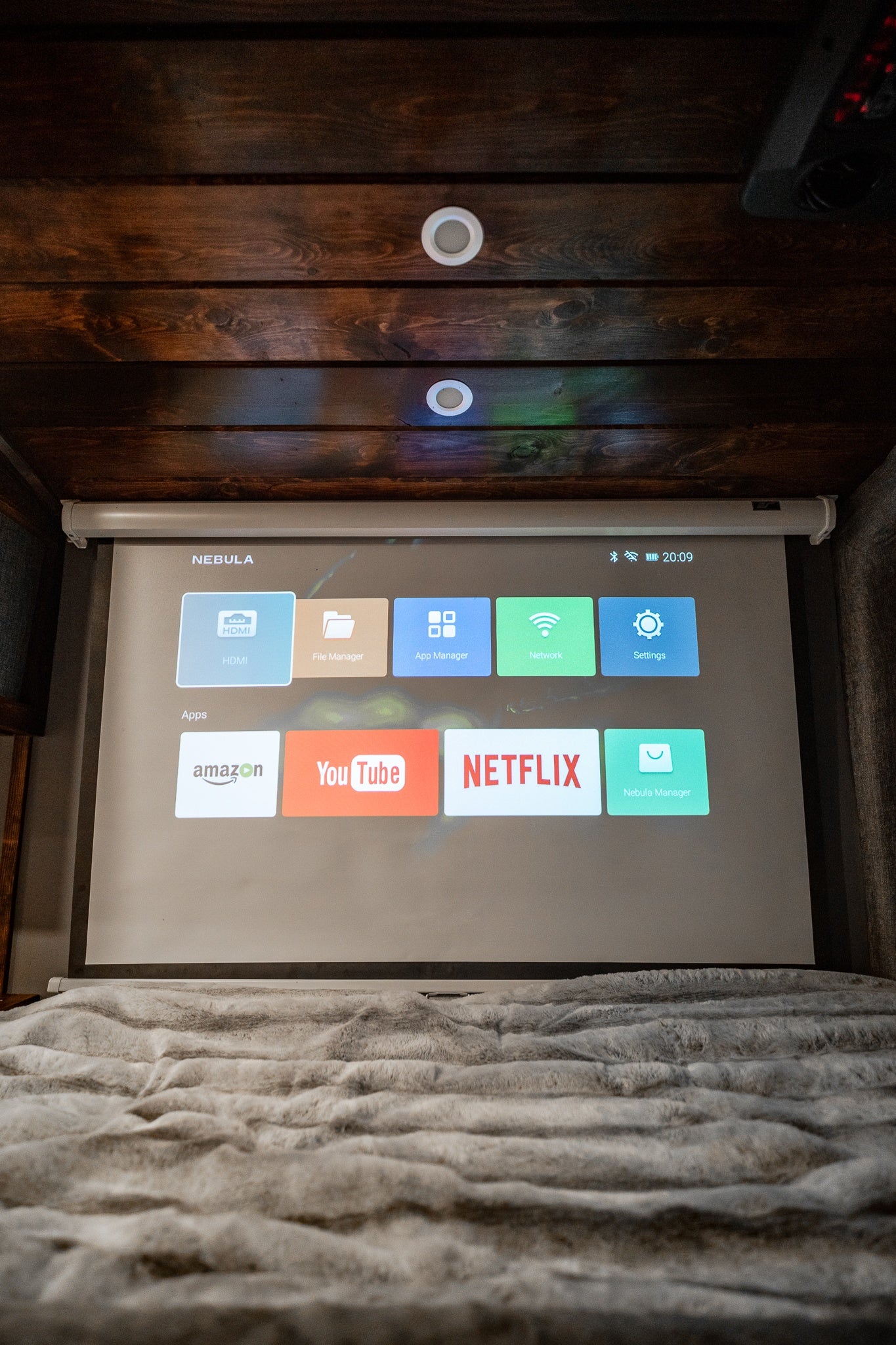 Cozy RV rental setup features a projector screen displaying streaming apps like Netflix & YouTube, ideal for entertainment.