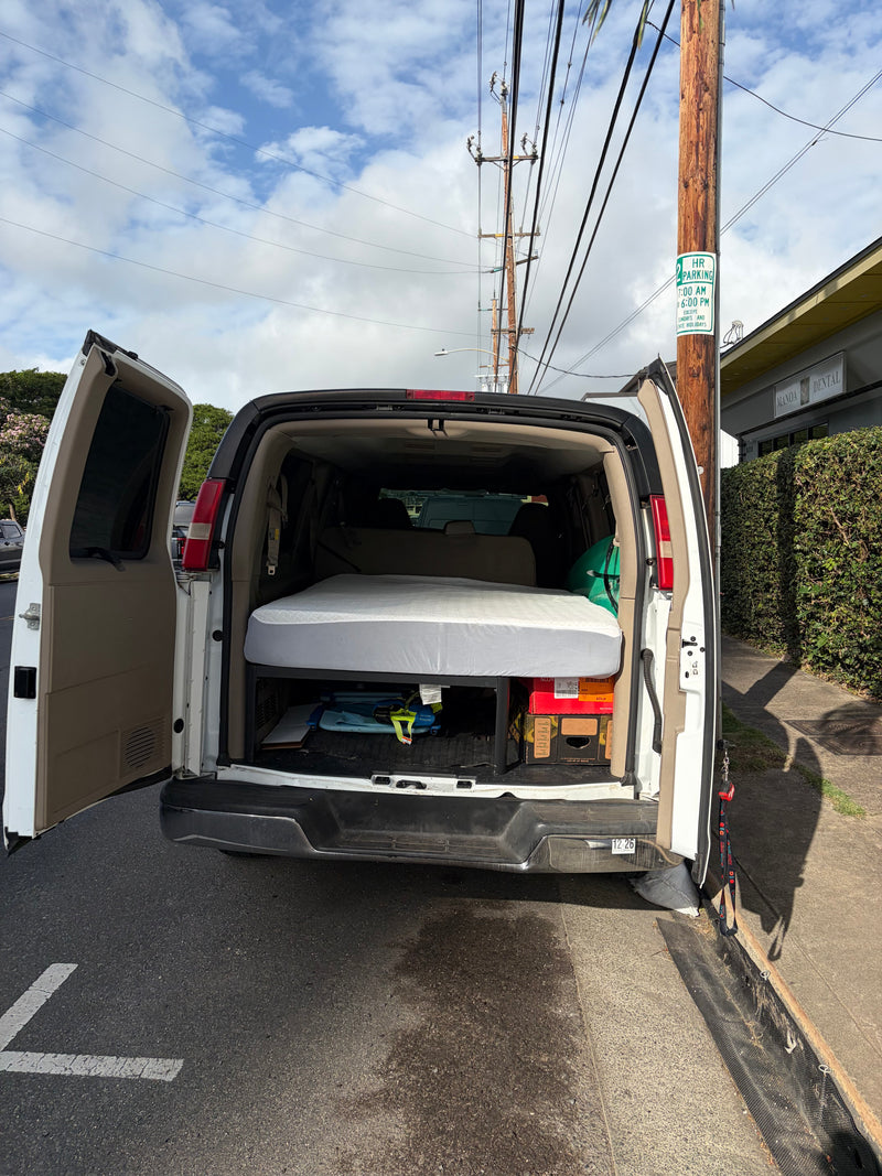 A white van, possibly an rv rental, is seen with its back doors open, revealing a mattress for sleeping, parked by a "2 HR PARKING" sign. — photo 2
