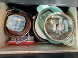 Organized kitchen drawer in an RV rental: pan, colander, pot, plates, & containers. Space-saving storage for camping.