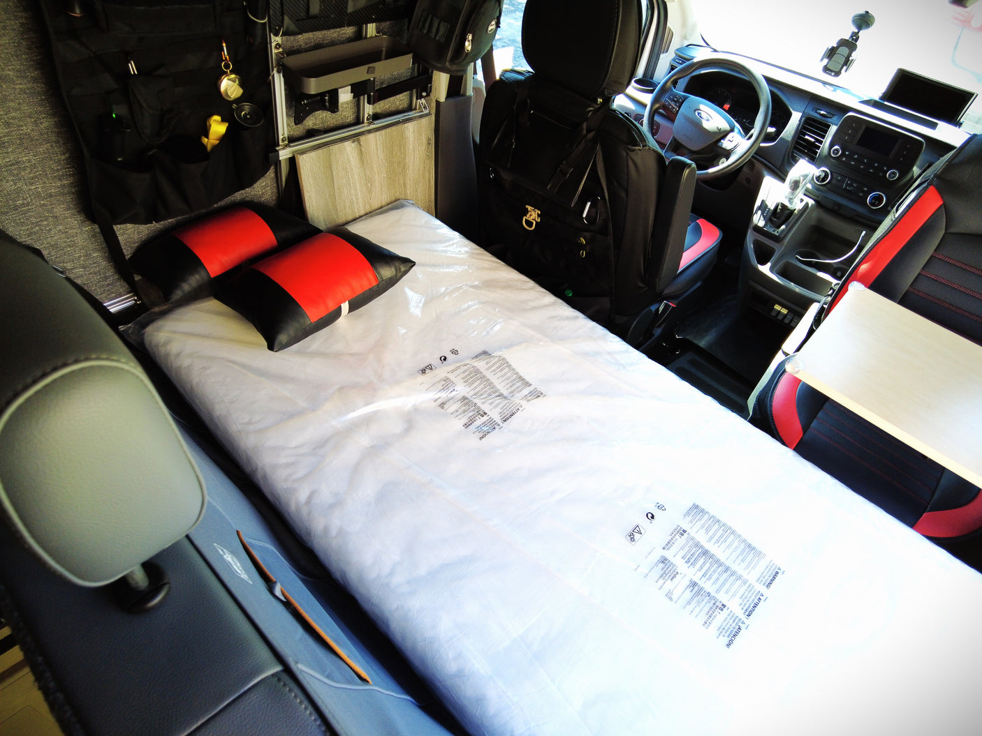 Inside a clean RV rental, featuring a new mattress, pillows, and versatile storage for travel.