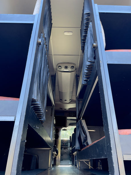 Inside an RV rental: Looking forward past multiple bunk beds with privacy curtains towards the cockpit.