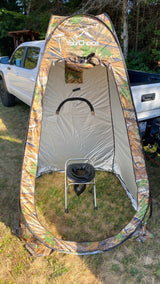 A camo privacy tent with a portable toilet inside, set up outdoors. Ideal for RV rental trips, camping, and outdoor comfort.