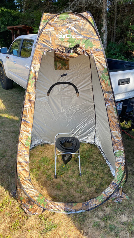 A camo privacy tent with a portable toilet inside, set up outdoors. Ideal for RV rental trips, camping, and outdoor comfort.