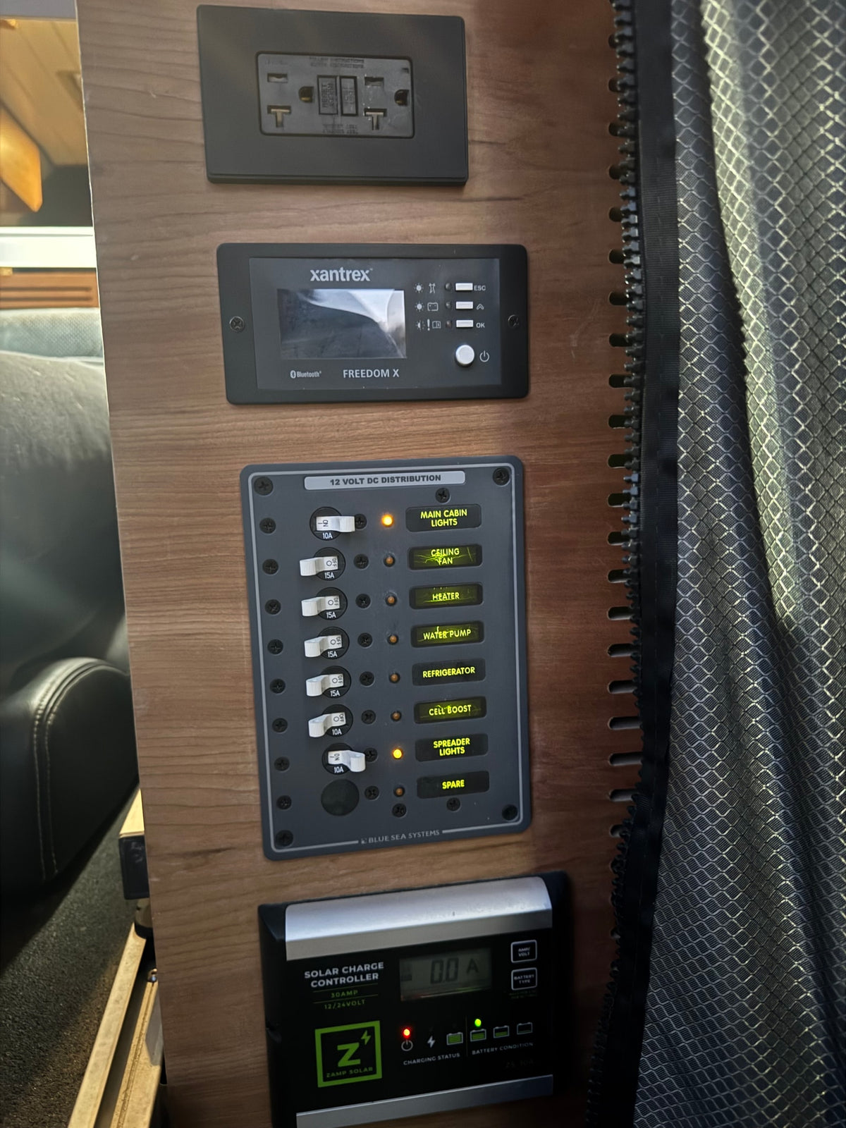  parked on a dirt road surrounded by pine trees. An ideal RV rental for outdoor adventures.|RV rental's main power controls: Xantrex inverter — photo 2