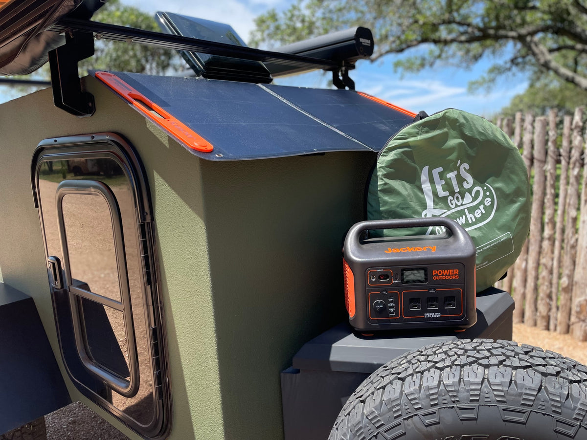 Green teardrop RV rental with solar panels, a Jackery power station, and camping bag, ready for outdoor adventures. — photo 6