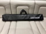 An Airstream branded accessory bag rests on a cream leather RV rental seat, ready for adventure.