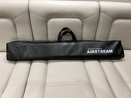 An Airstream branded accessory bag rests on a cream leather RV rental seat, ready for adventure.