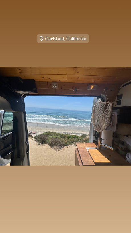 RV rental in Carlsbad, CA: Van's open doors frame a sunny beach and ocean view. Perfect for coastal adventures.