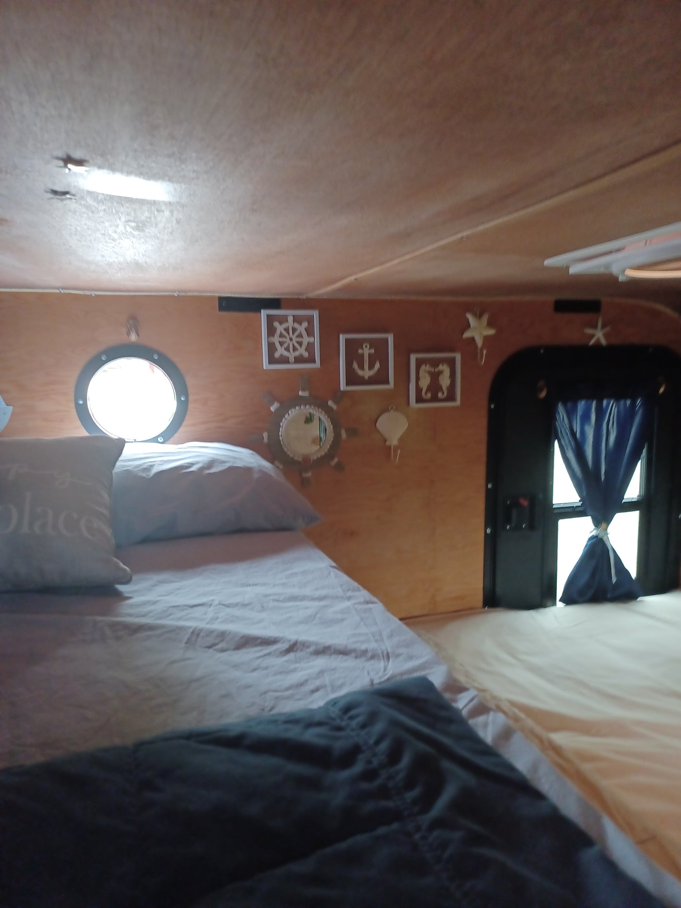 RV rental: Cozy nautical-themed bedroom with a bed, porthole window, and ocean decor on wood-paneled walls. — photo 15