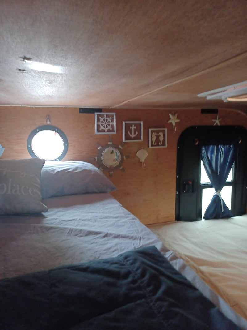 RV rental: Cozy nautical-themed bedroom with a bed, porthole window, and ocean decor on wood-paneled walls. — photo 15