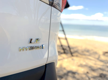 White LE Hybrid SUV near an rv rental on a sunny beach. Ideal for scenic coastal travel and outdoor adventures.