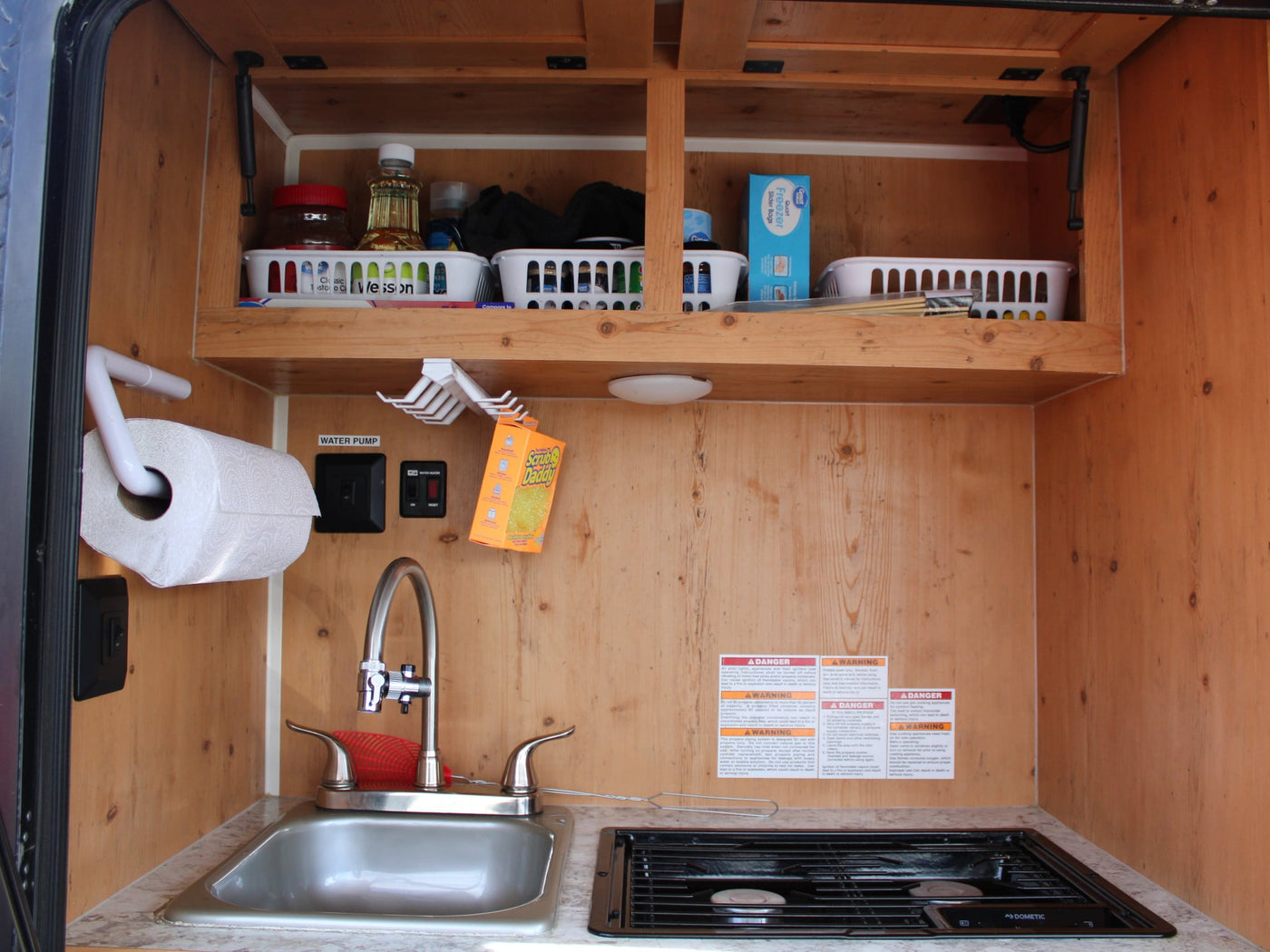  and an "EXIT" sign.|Inside an RV rental: a comfortable red and white dinette with wood walls and a plaid pillow — photo 7