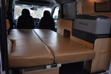 Inside an RV rental camper van: comfortable tan bed cushions, custom wood interior, and a Dometic fridge. Ready for adventure!
