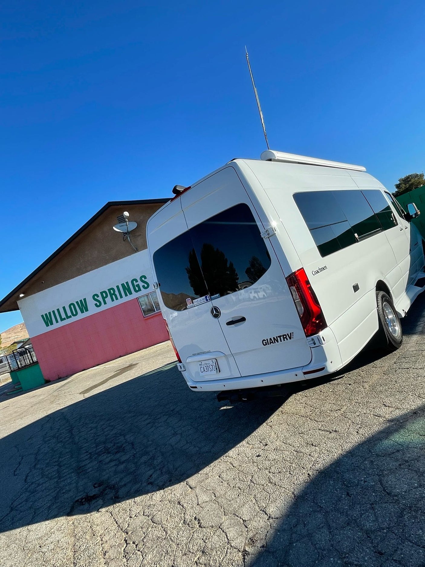 Bright blue sky over a white Mercedes Sprinter rv rental, branded Coachmen, parked at Willow Springs.