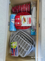 RV rental kitchen drawer with essential camping supplies: matches, food containers, and collapsible kitchenware.