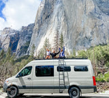 Joyful family on an RV rental van's roof, arms raised, against Yosemite's majestic El Capitan. Epic van life!