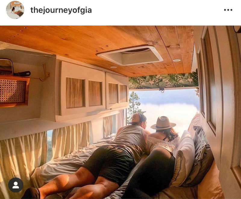 Imagine this RV rental! A couple enjoys a misty scenic view from their comfortable bed inside a beautifully designed camper van. — photo 9