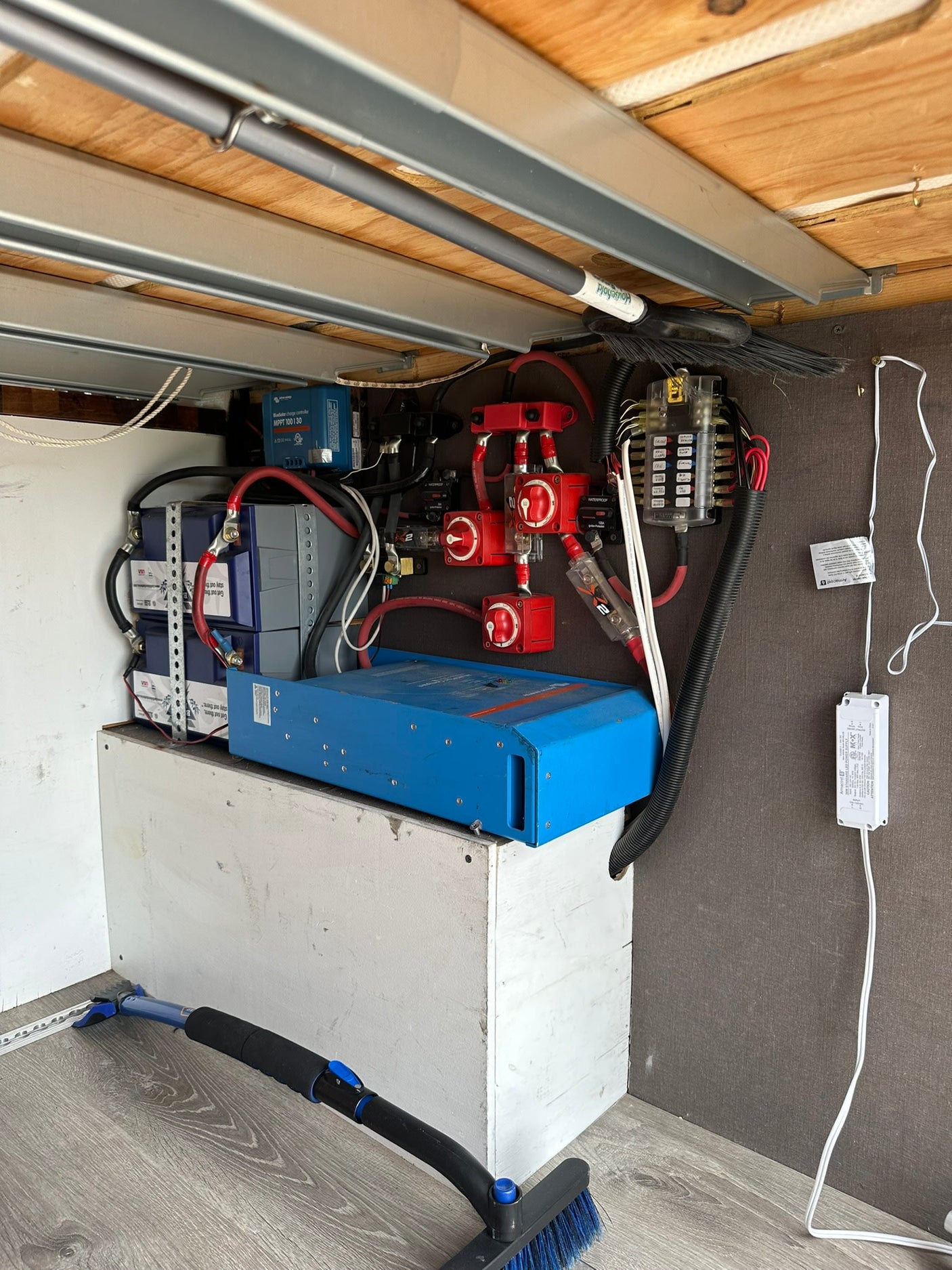 Inside an RV rental: a robust electrical system. Features stacked lithium batteries, a blue inverter, charge controller, and red switches.
