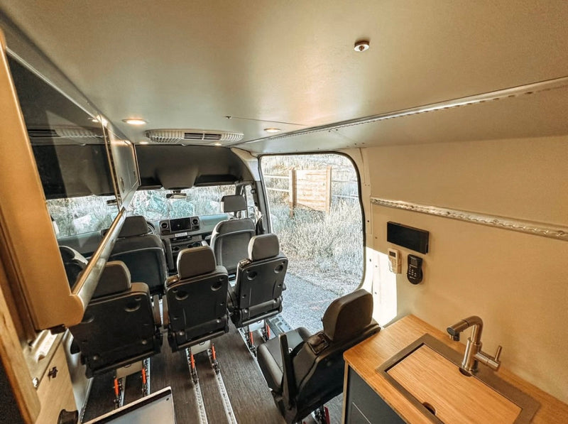  parked in sunny desert with hills.|Spacious RV rental interior featuring a cozy bed with plaid bedding — photo 2