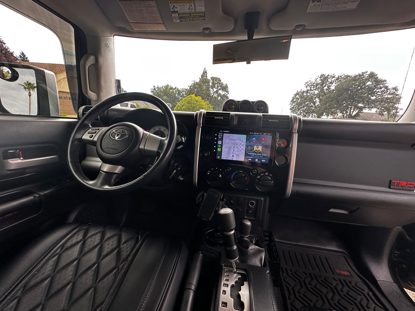 Inside an FJ Cruiser: driver's seat, dashboard with navigation, and view outside. Ready for your next **rv rental** adventure.