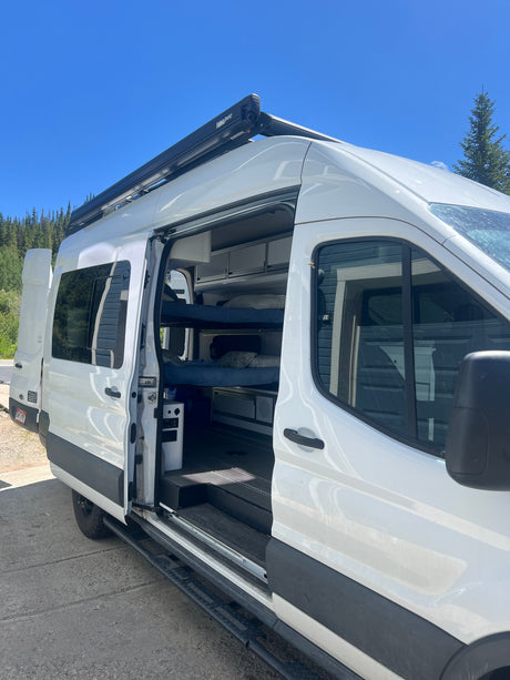 White camper van rv rental with open door revealing bunk beds and interior. Ideal for your next adventure.