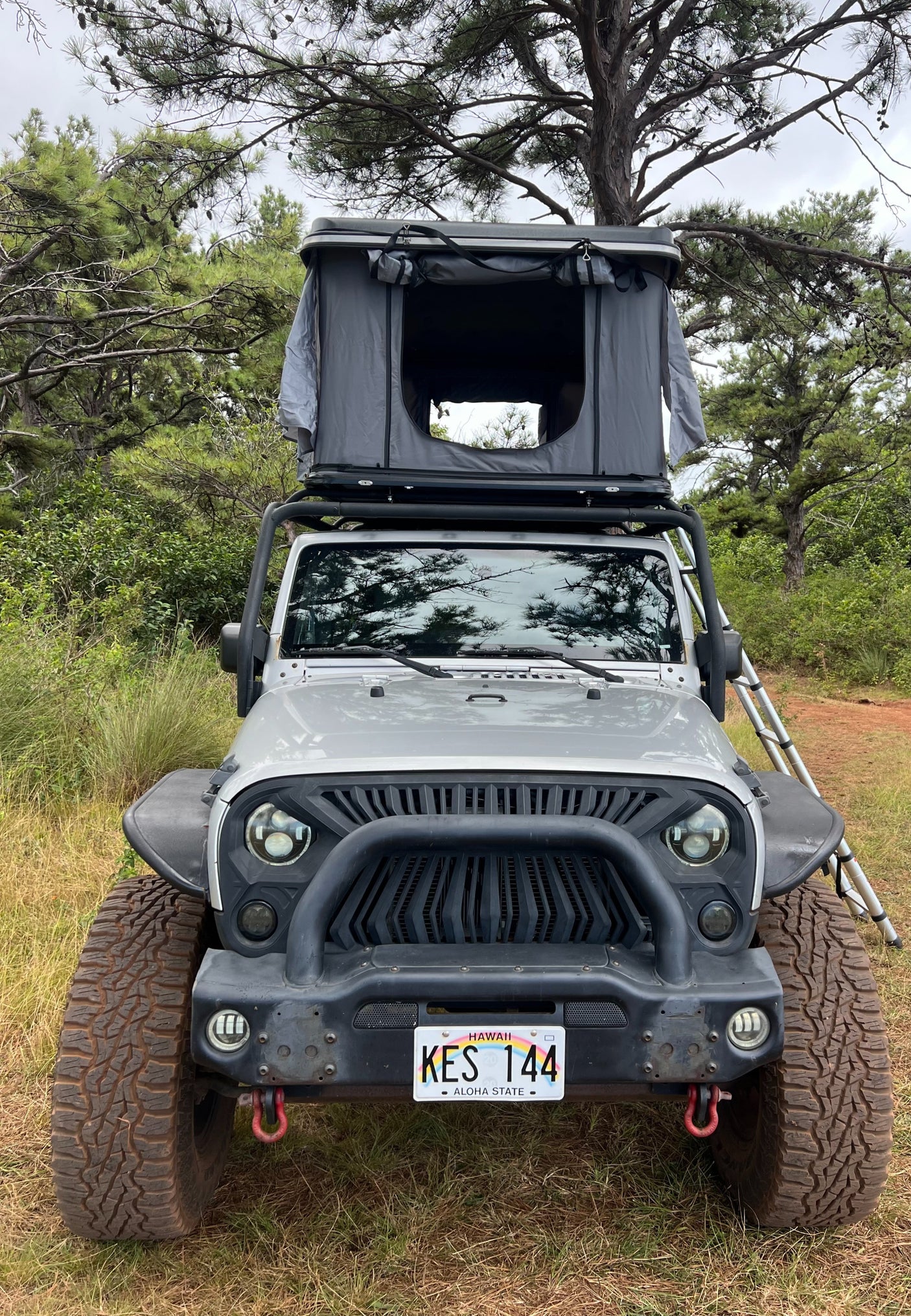Grey Jeep Wrangler with rooftop tent, ideal for a unique RV rental camping adventure in Hawaii.