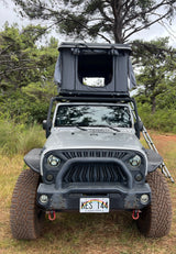 Grey Jeep Wrangler with rooftop tent, ideal for a unique RV rental camping adventure in Hawaii.