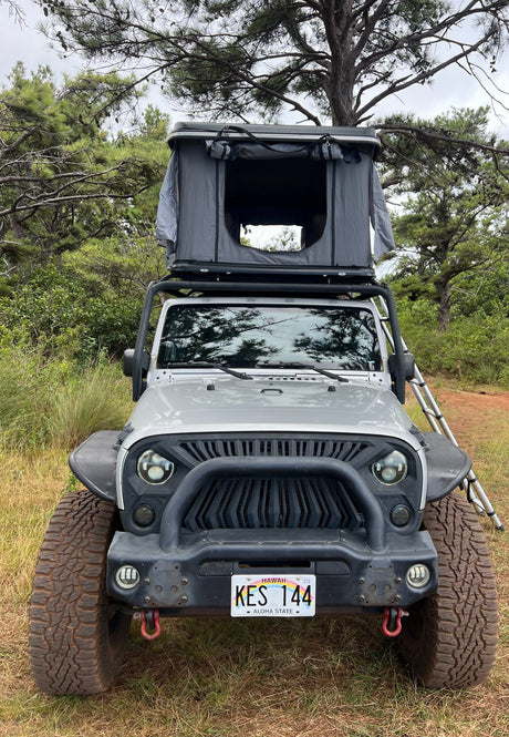 Grey Jeep Wrangler with rooftop tent, ideal for a unique RV rental camping adventure in Hawaii.