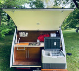 This RV rental's open rear galley showcases a compact outdoor kitchen with sink, stove, and portable fridge for camping.