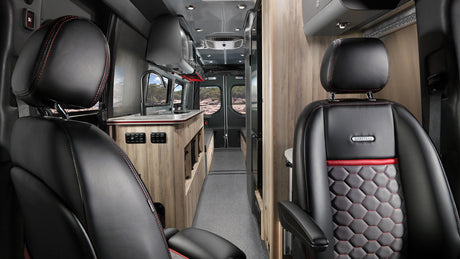 Airstream RV rental interior showing luxury black leather seats, red accents, and a modern galley kitchen.