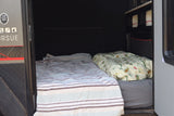 Cozy RV rental sleeping area with two beds and adventure gear storage. Perfect for travel trailer trips.