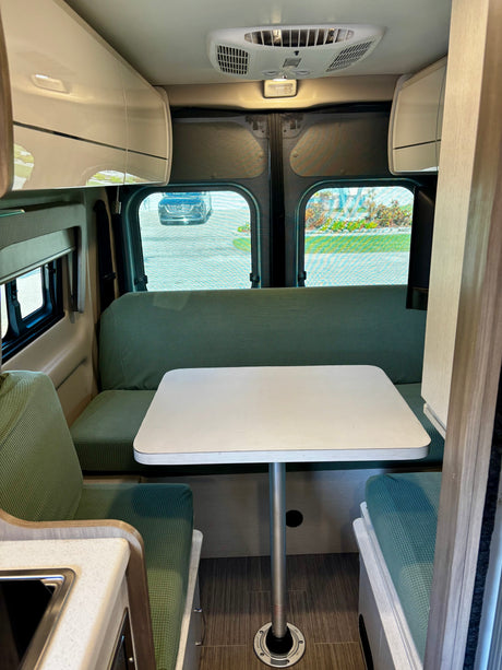 Cozy rv rental interior: inviting dinette with green cushions, overhead cabinets, and outdoor views.