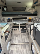 Cozy, functional rv rental interior with a bed, dinette, kitchen, and Dometic cooler, perfect for travel adventures.
