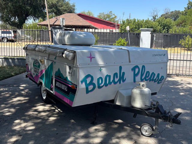 This colorful pop-up camper from an RV rental service features "Beach Please" art