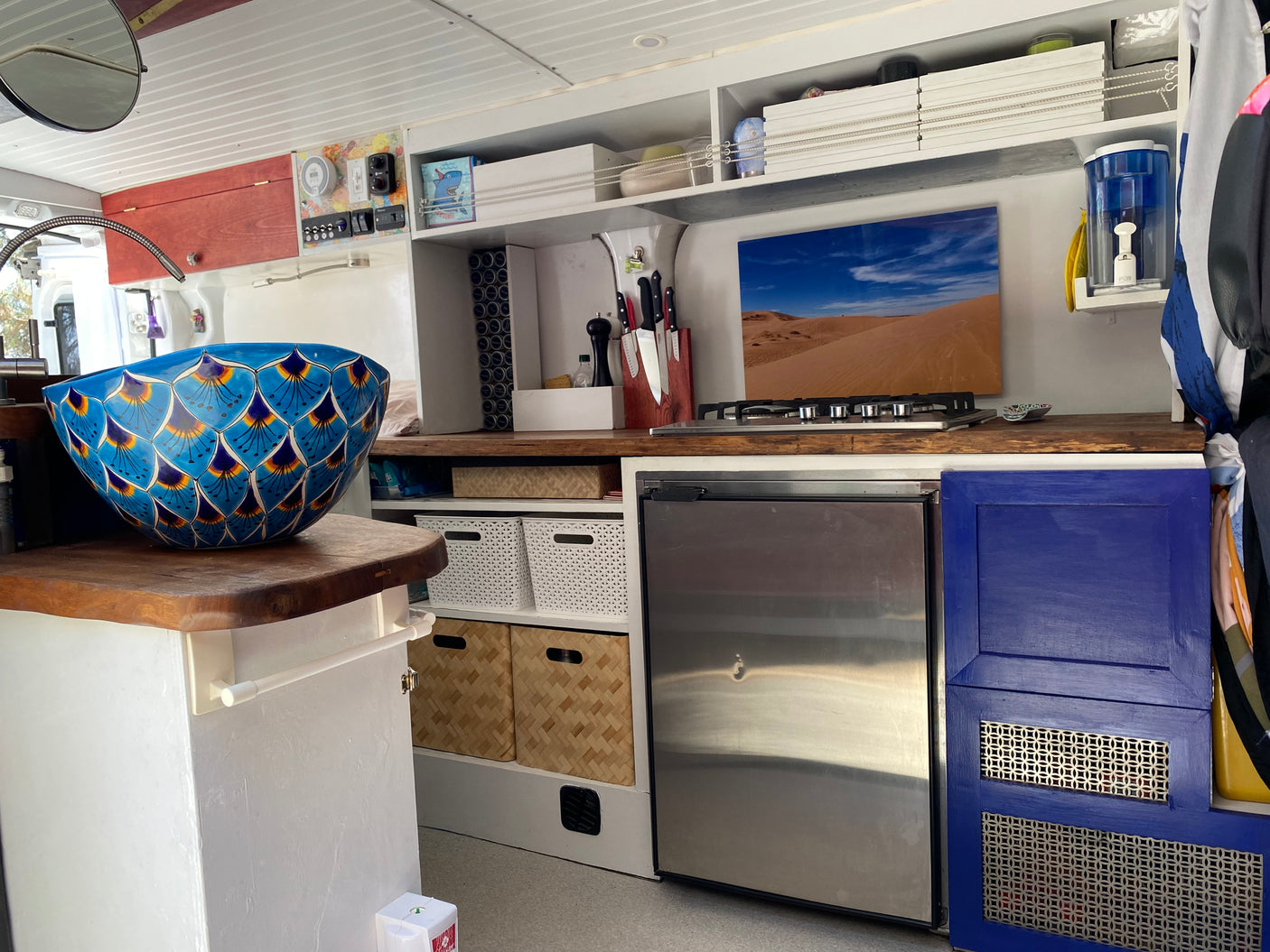 Spacious RV rental kitchen featuring a vibrant blue sink, gas stove, fridge, and ample storage, perfect for your next adventure.