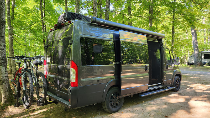 RV rental: Dark grey camper van with bikes on the rack & open side door, parked at a lush green campsite. — photo 4