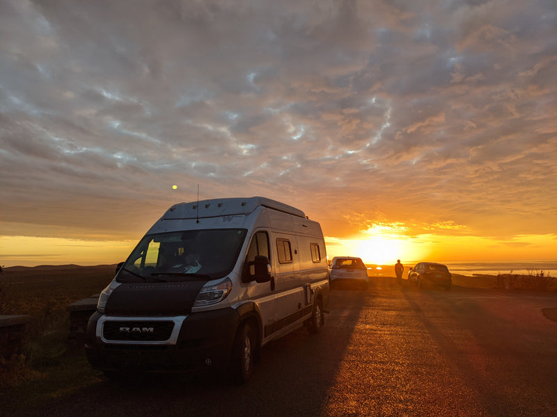 An RV rental basks in the golden light of sunset at a scenic overlook. Distant waters and hills offer a beautiful road trip view. — photo 8