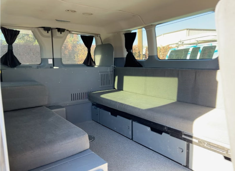  sliding door open to reveal interior swivel seat. Custom artistic wrap visible on side.|Inside an RV rental van: three black passenger seats — photo 4