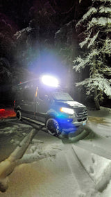Experience winter van life! This bright RV rental is parked deep in a snowy forest at night, ready for adventure.