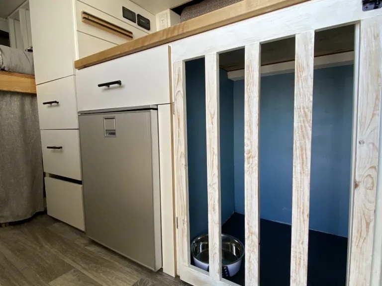 RV rental interior: Pet-friendly camper van with built-in dog crate, fridge, and storage drawers.