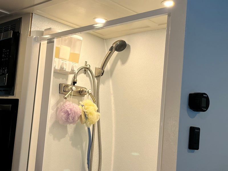 Compact RV rental shower featuring wall-mounted soap dispensers, loofahs, and shower controls for a convenient travel experience. — photo 7