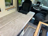 Explore this RV rental's cozy interior: bed, window, and driver's area with dashboard and swivel seat.