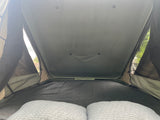 Looking up at the cozy sleeping area within an RV rental rooftop tent, featuring pillows and soft bedding.