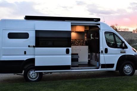 This white camper van, available for rv rental, shows its custom interior with a mobile kitchen, perfect for van life adventures.